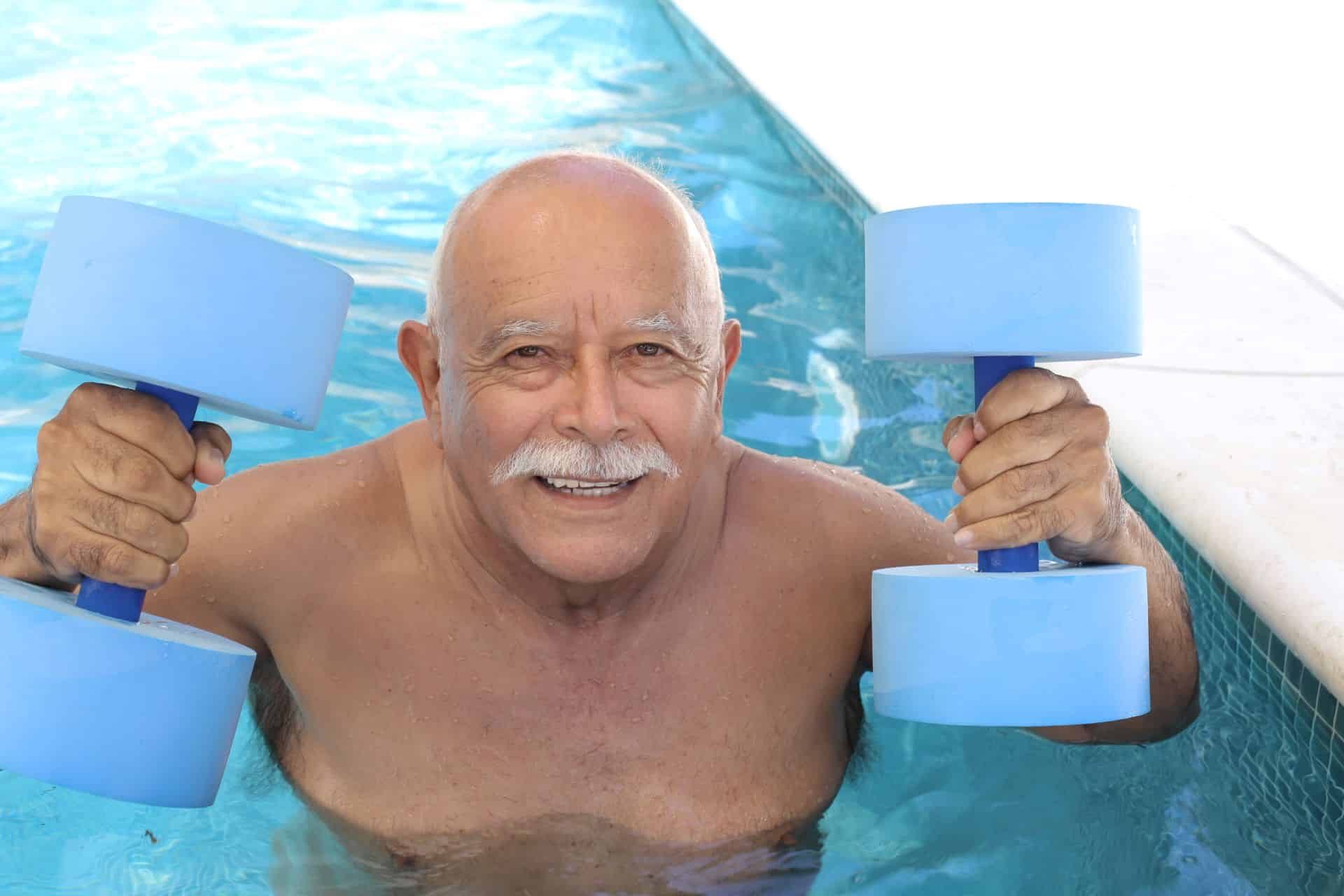 Senior trainiert mit blauen Aqua-Hanteln im Pool.