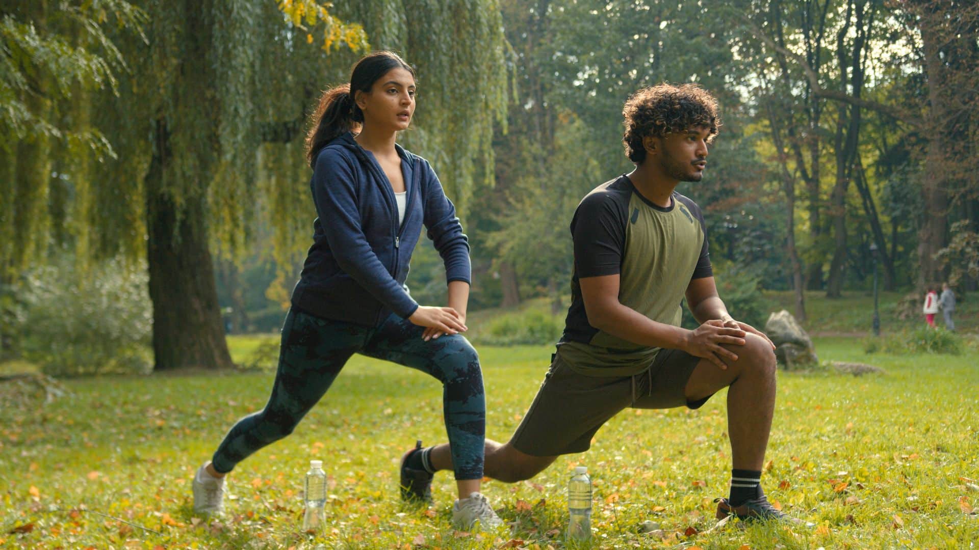 Zwei Personen beim gemeinsamen Outdoor-Workout im Park, mit einer schattigen Umgebung, ideal in Kombination mit Gartenpavillons.