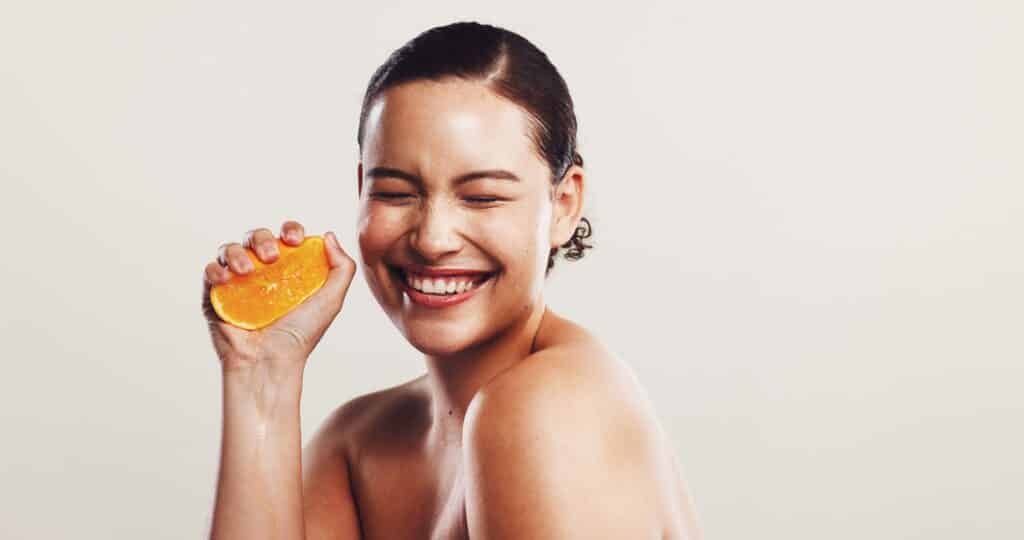 Lachende Frau mit Orange | Pigmentflecken entfernen