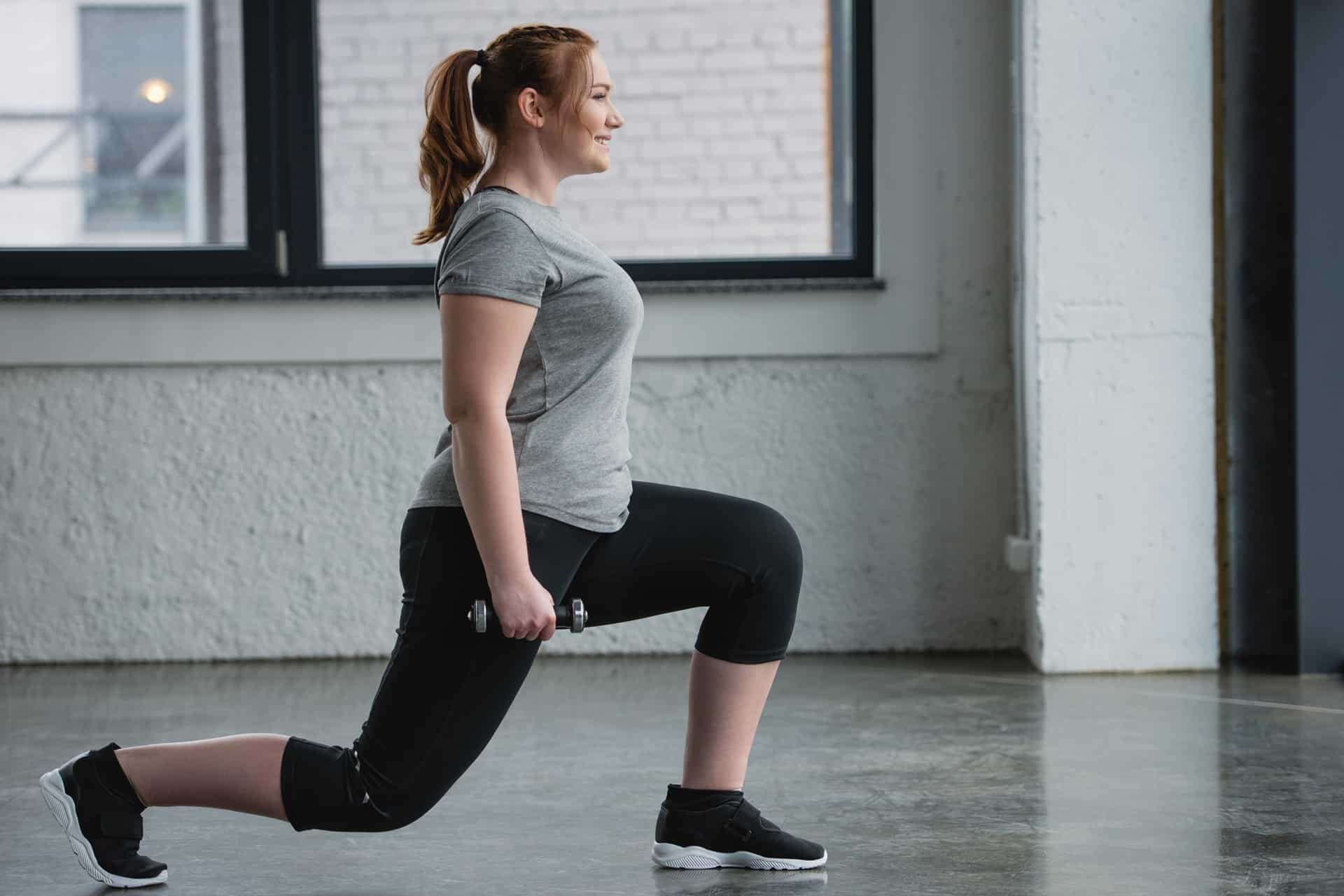 Frau beim Ausfallschritt mit Zopf im Fitnessstudio | Haarteile

