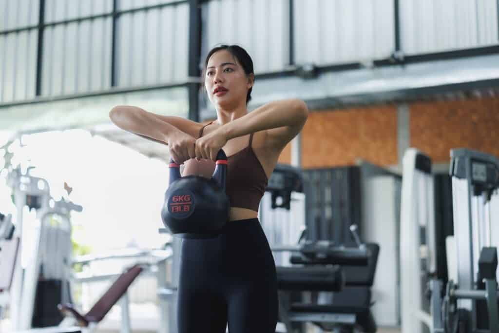 Frau trainiert mit Kettlebell im Fitnessbereich | Haarteile